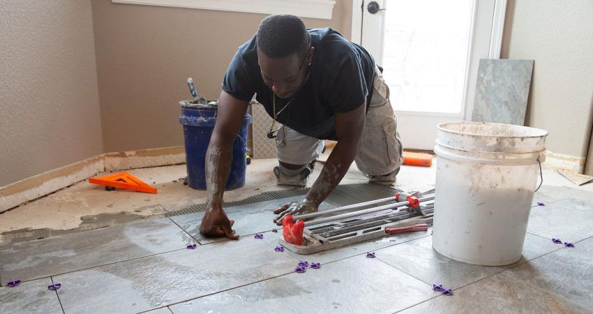 African American male laying ceramic tile